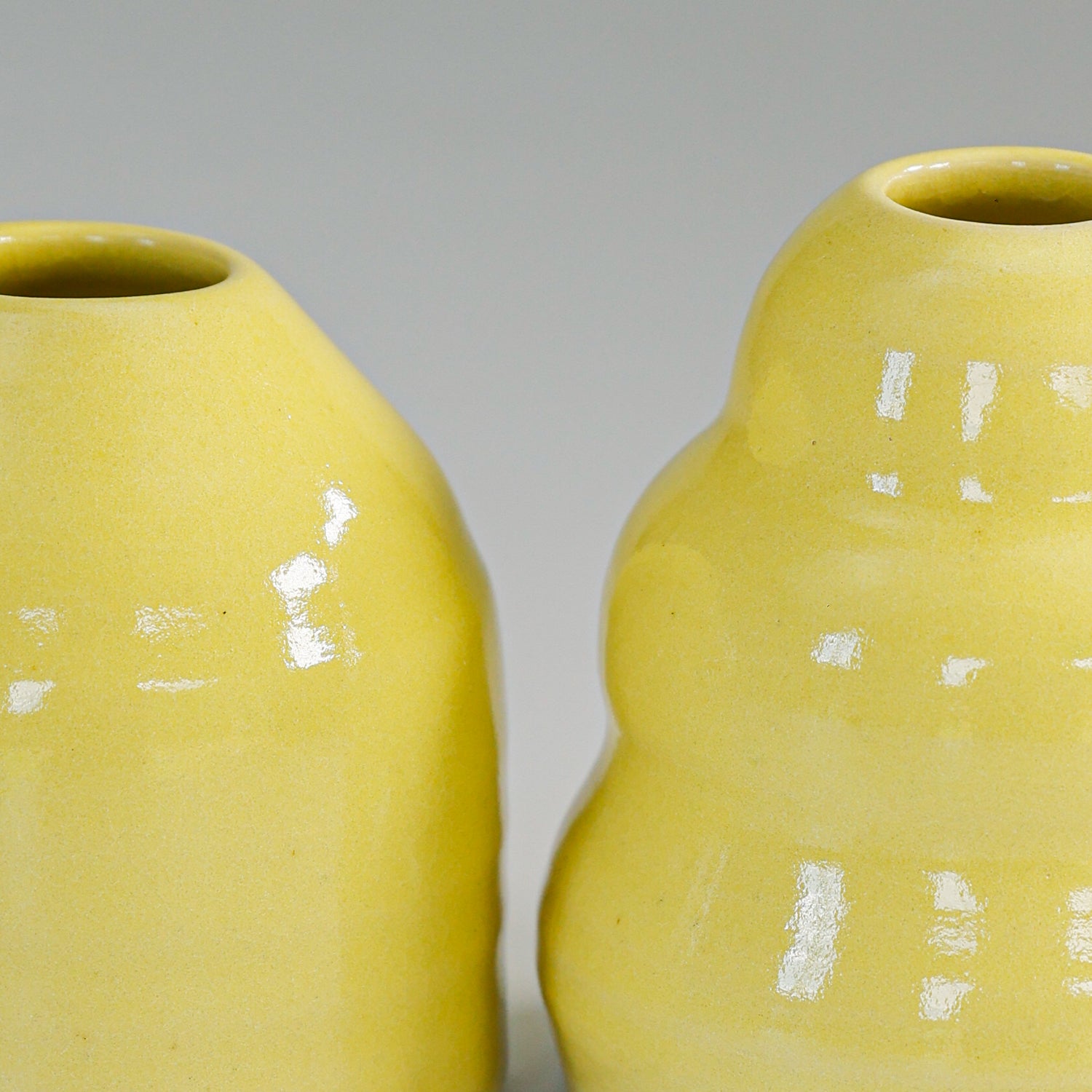 Close up of glazing of small yellow pottery bud vases 