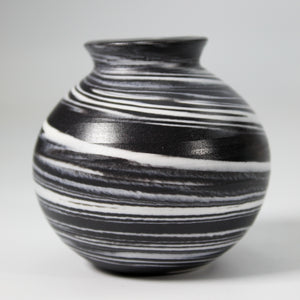 Close up of handmade ceramic mini moon jar glazed in black with white swirls