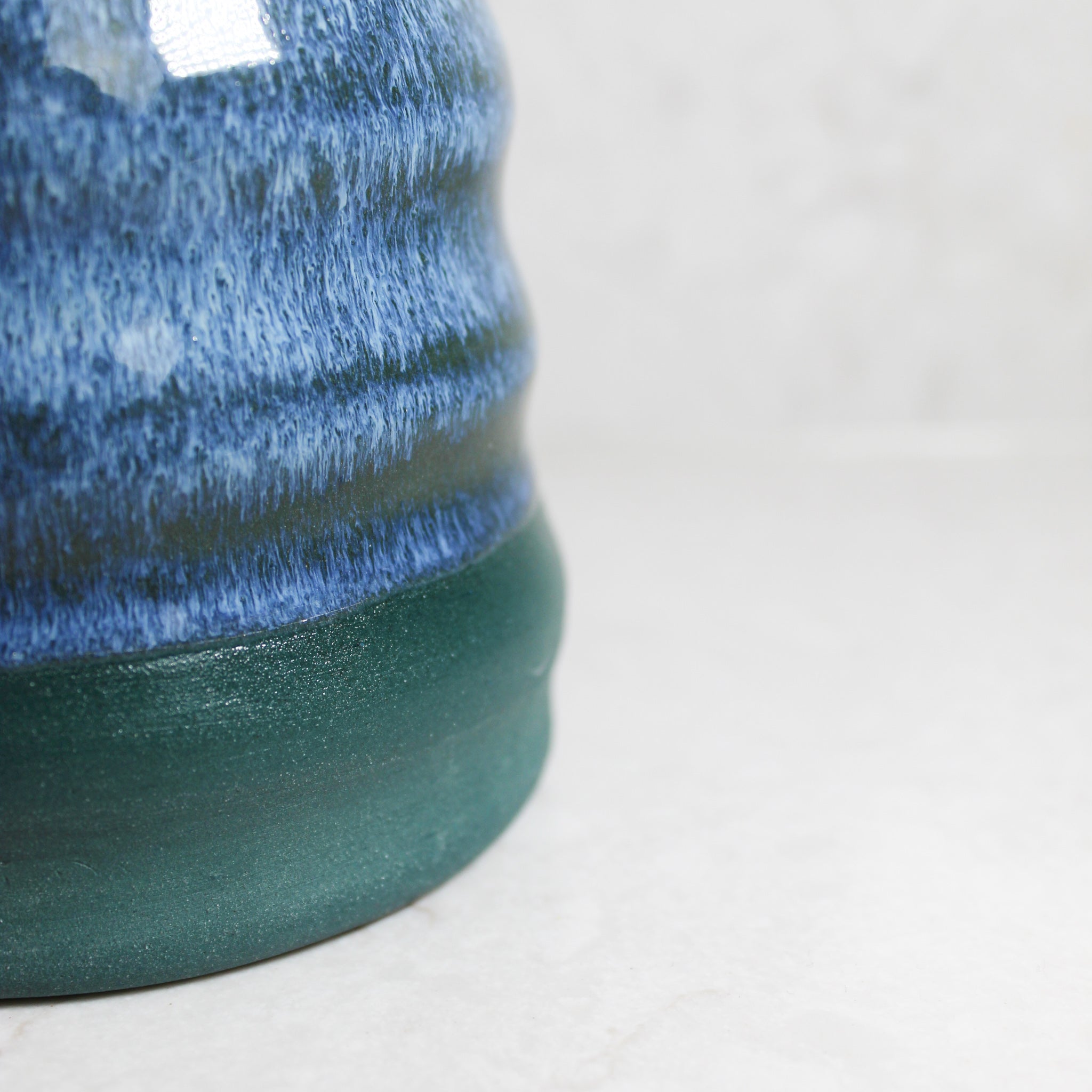 Close up of bottom section of pottery mini wobble vase in green and blue