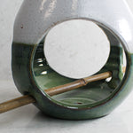Load image into Gallery viewer, Close up of inside of pottery green and white bird feeder with bamboo perch 
