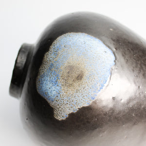 Close up of blue detailing on small black vase