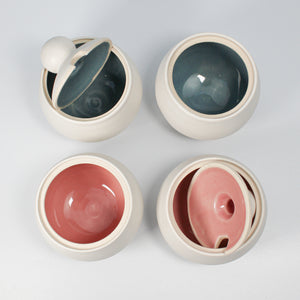 Four white pottery sugar bowls. Two have blue gloss inners, two have pink gloss inners