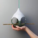 Load image into Gallery viewer, Hand holding ceramic green and white bird feeder with bamboo perch 

