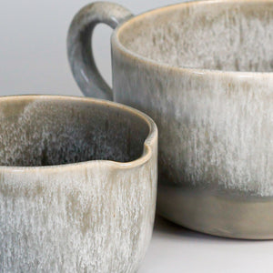 Close up of glazing detail on pair of grey glazed ceramic gravy jugs 