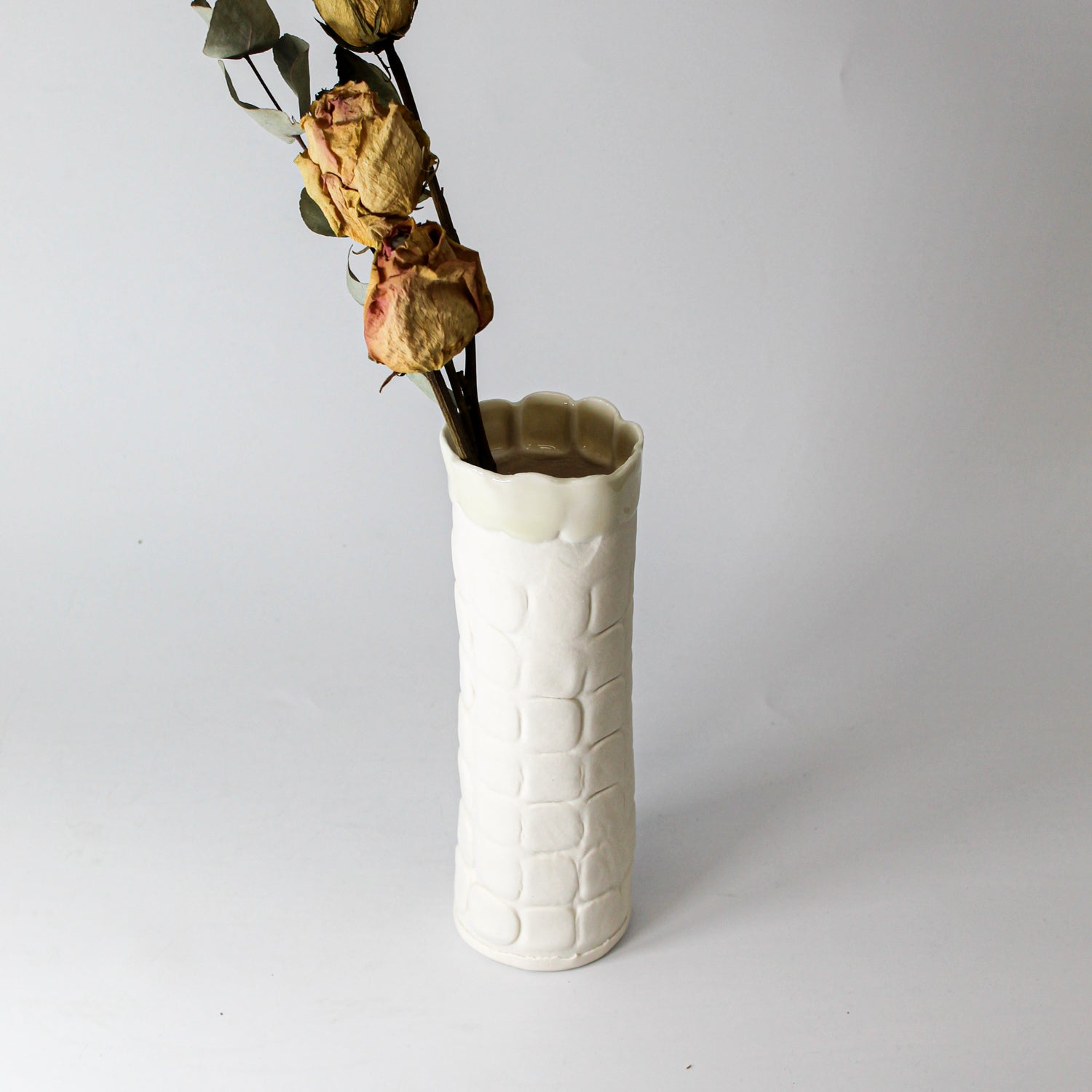 White handmade porcelain vase with dried flowers in