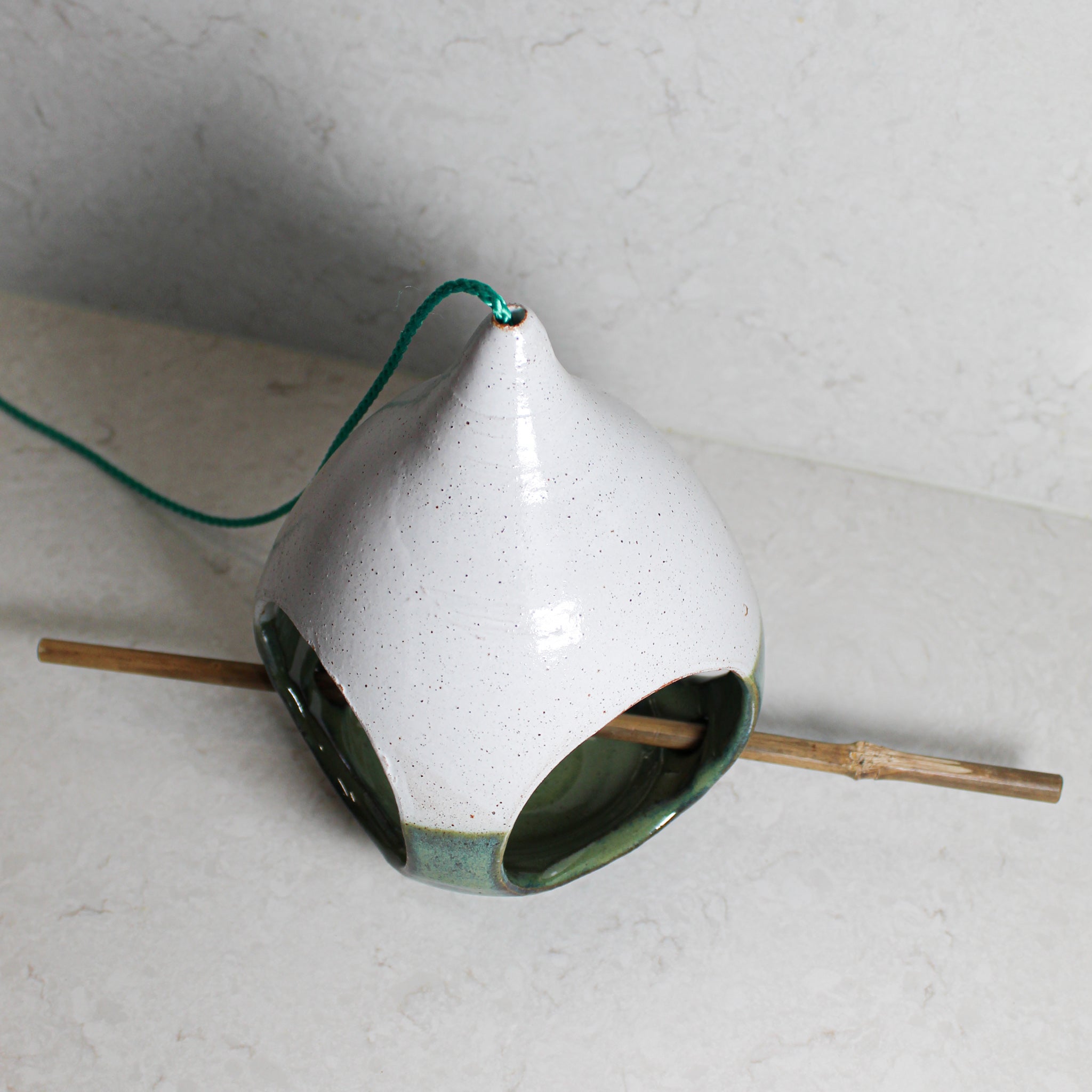 View from above of pottery green and white bird feeder with bamboo perch 