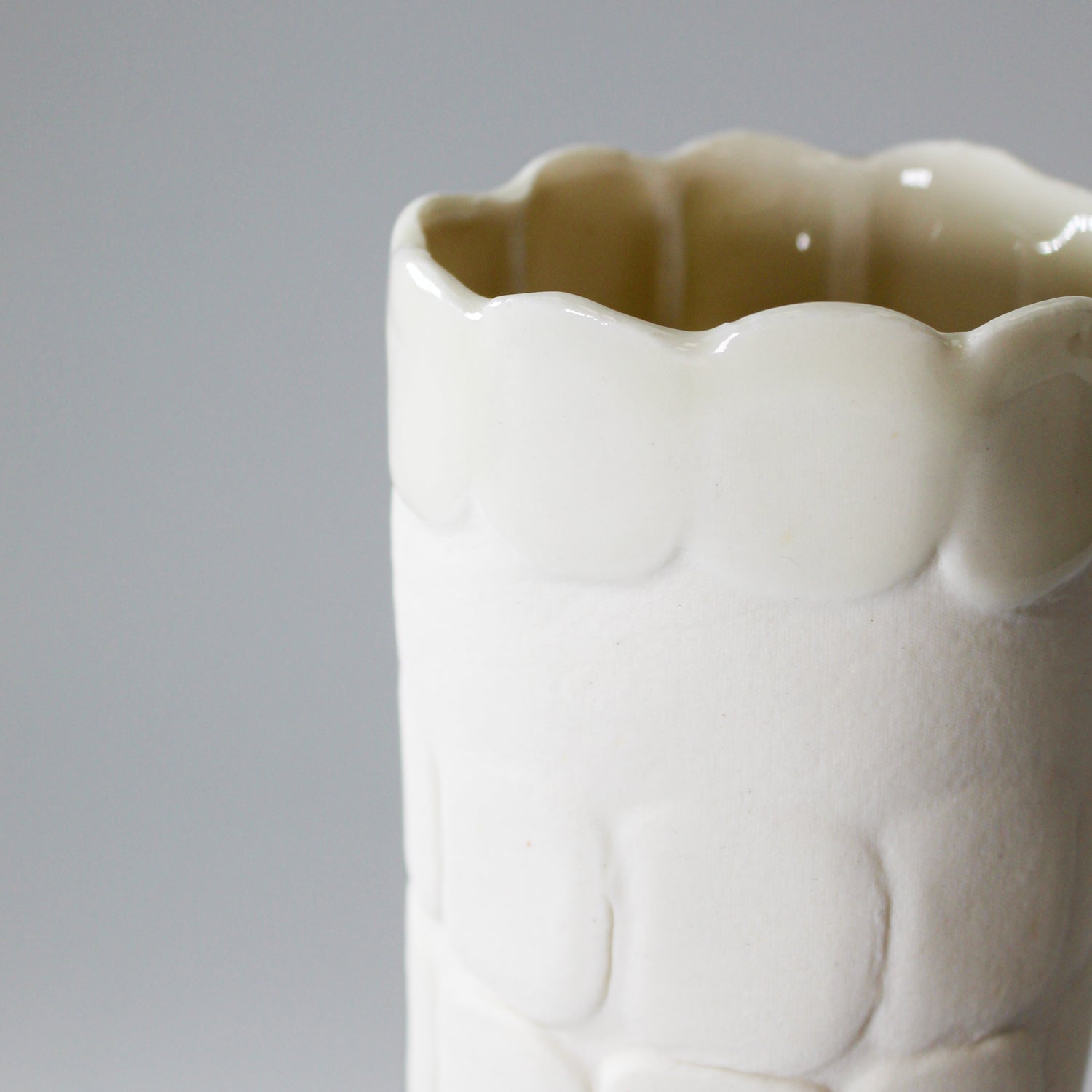 Close up of top of tall slim white handmade porcelain vase 